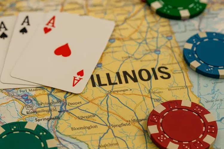 A realistic close-up photograph of poker chips and playing cards placed over a detailed map of Illinois.